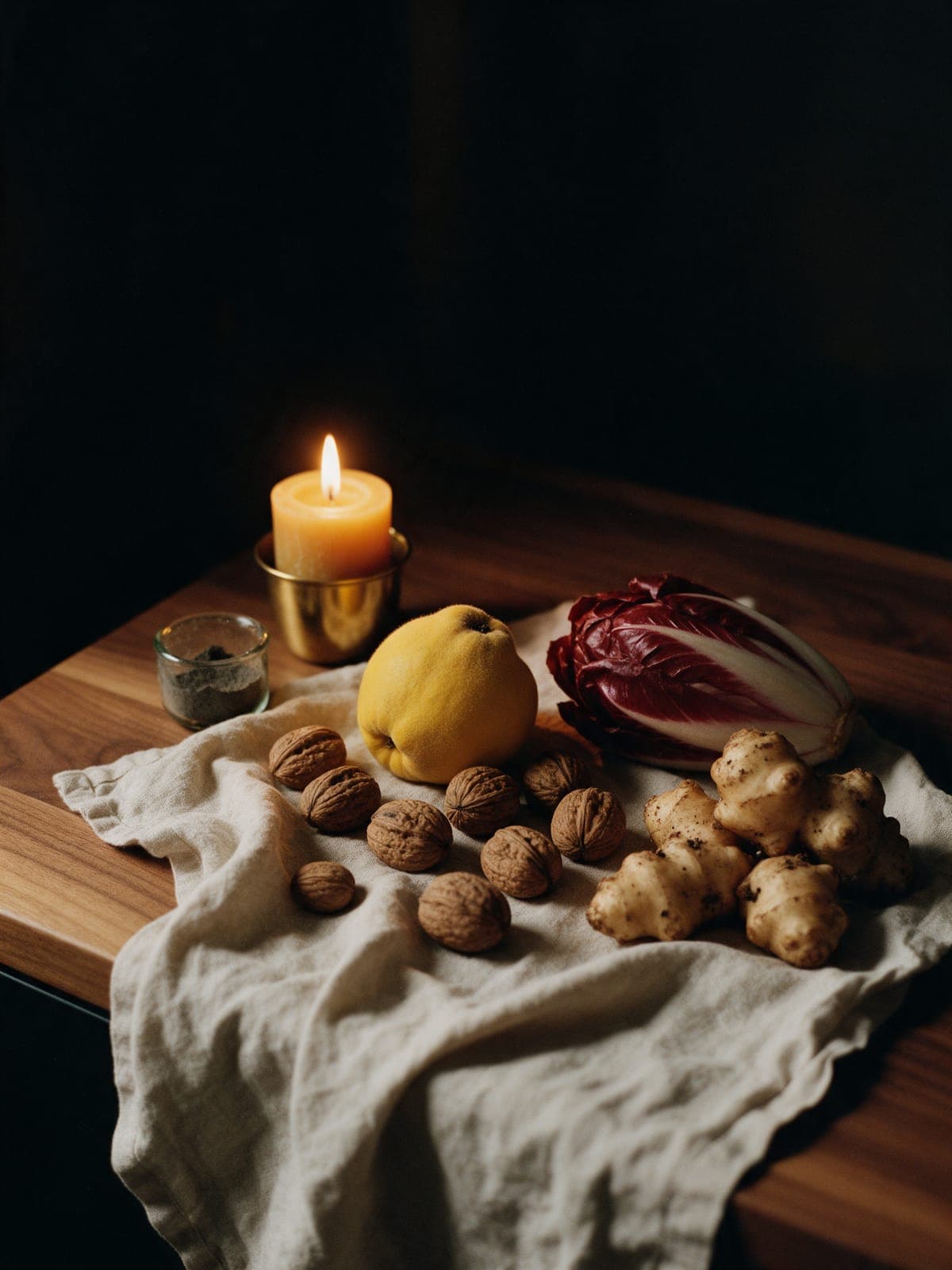 Quince, walnuts in their shells, a head of red chicory and earthy sunchokes on undyed linen, one candle.