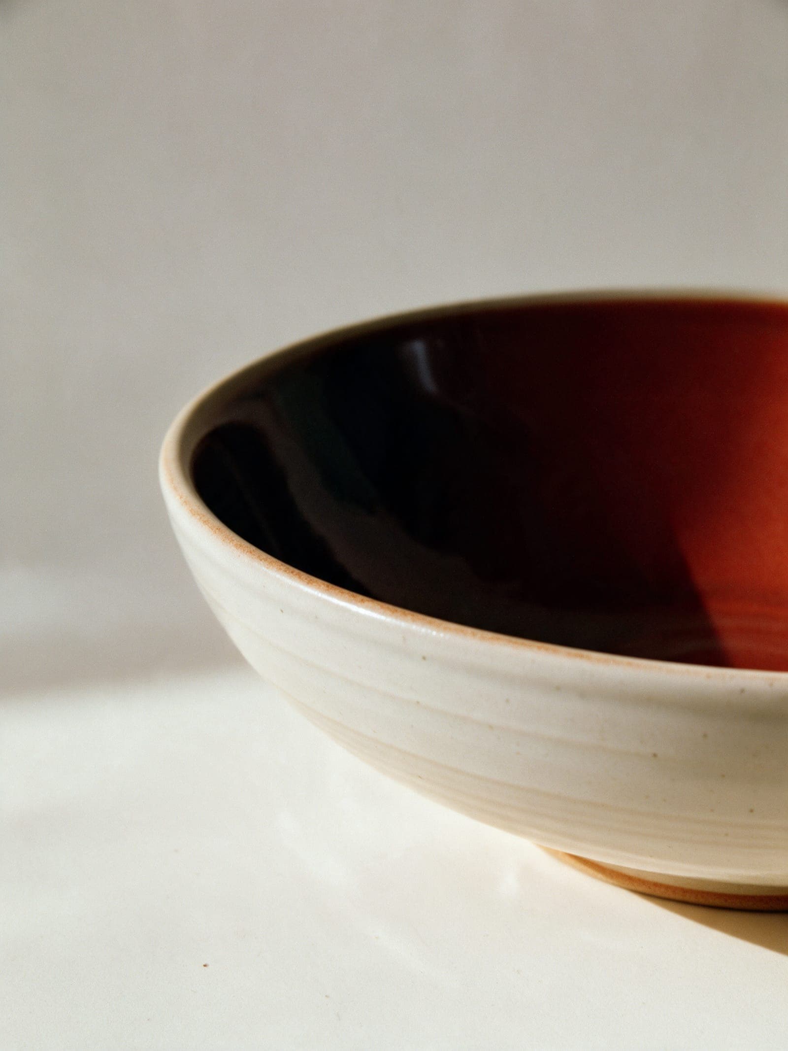 The rim of the Low Bowl: kaki breaking dark where it thins, oatmeal outside
