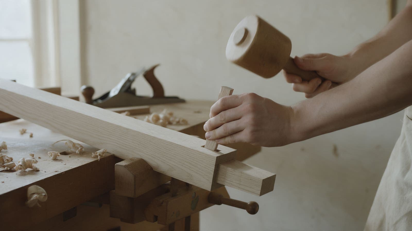 A joiner driving an oak peg through a trestle joint