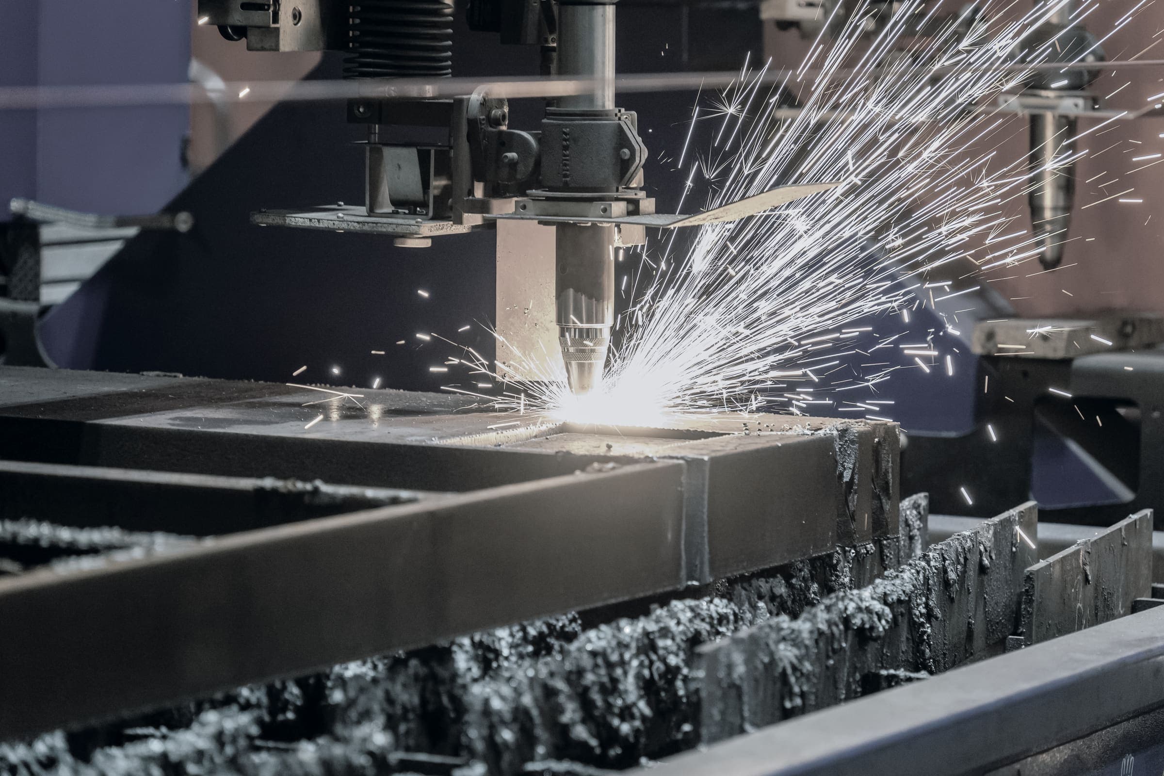 The cutting head piercing steel plate on the slat table, a fan of sparks thrown off the cut