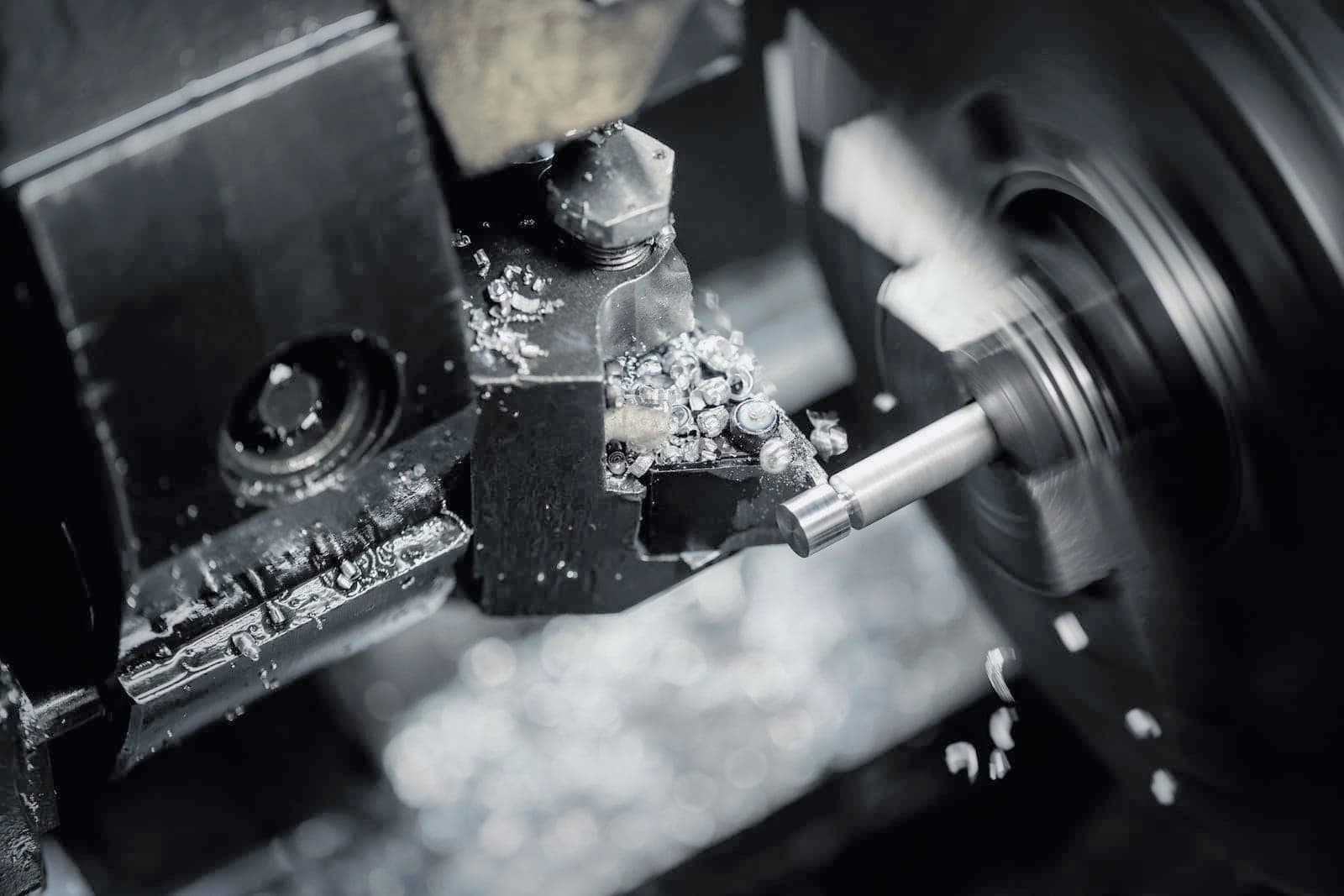 Turning insert cutting a shaft on the lathe, bright chips piled on the tool