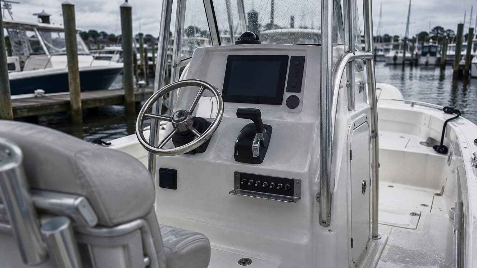 A polished stainless bracket under the dash of a center-console boat helm, holding a row of toggle switches
