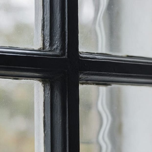 The corner of a black painted wood window sash.