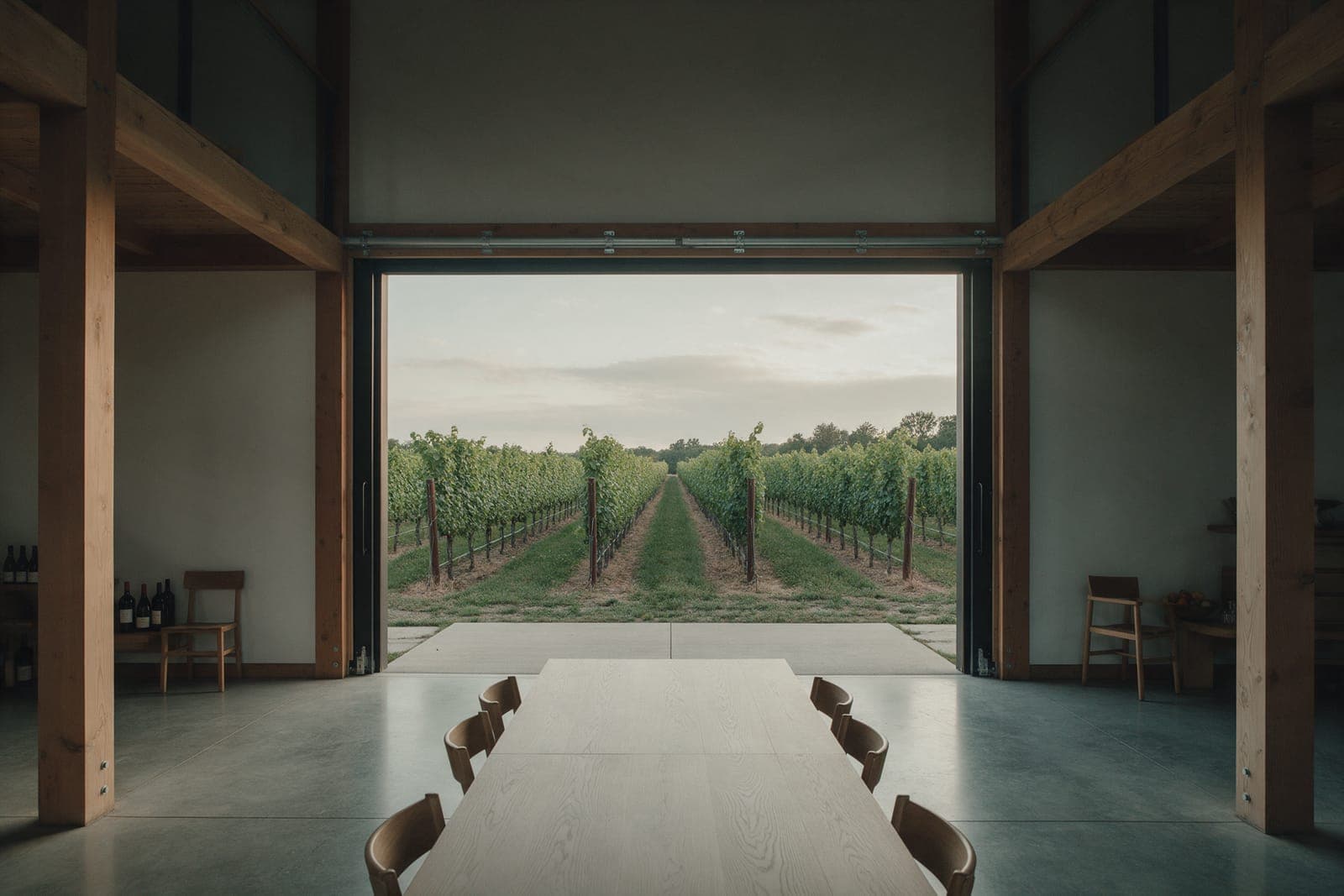 The main room of Vineyard Barn House looking out through the 11-foot sliding door, rolled open on the vine rows.