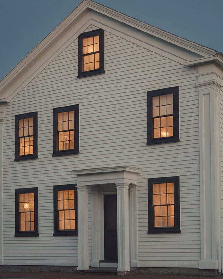 The restored entry of Whaler's Cottage: pilasters, a plain frieze and six-over-six sash.