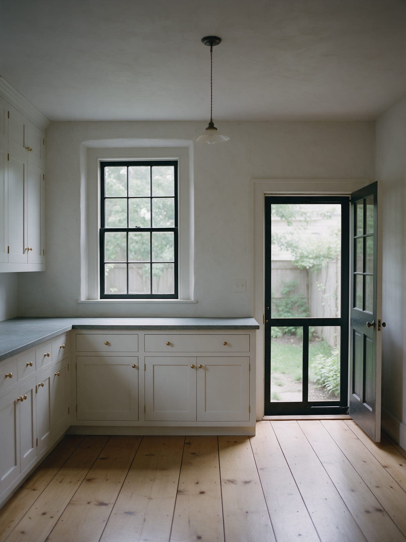 The new kitchen at the back of Whaler's Cottage: painted cabinets, wide pine floor and a glass door to the yard.