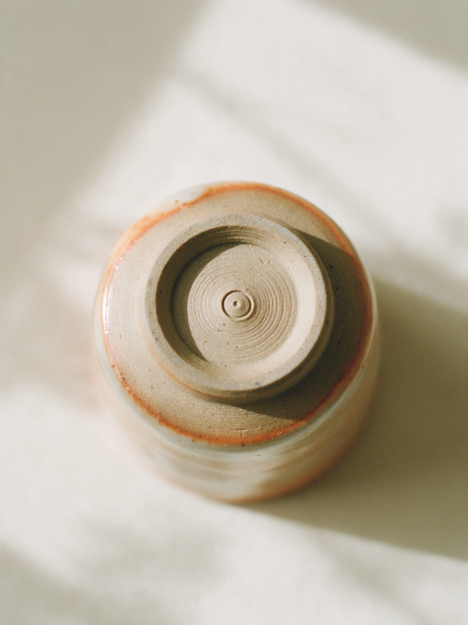 The trimmed foot ring, raw clay, with the studio mark pressed in