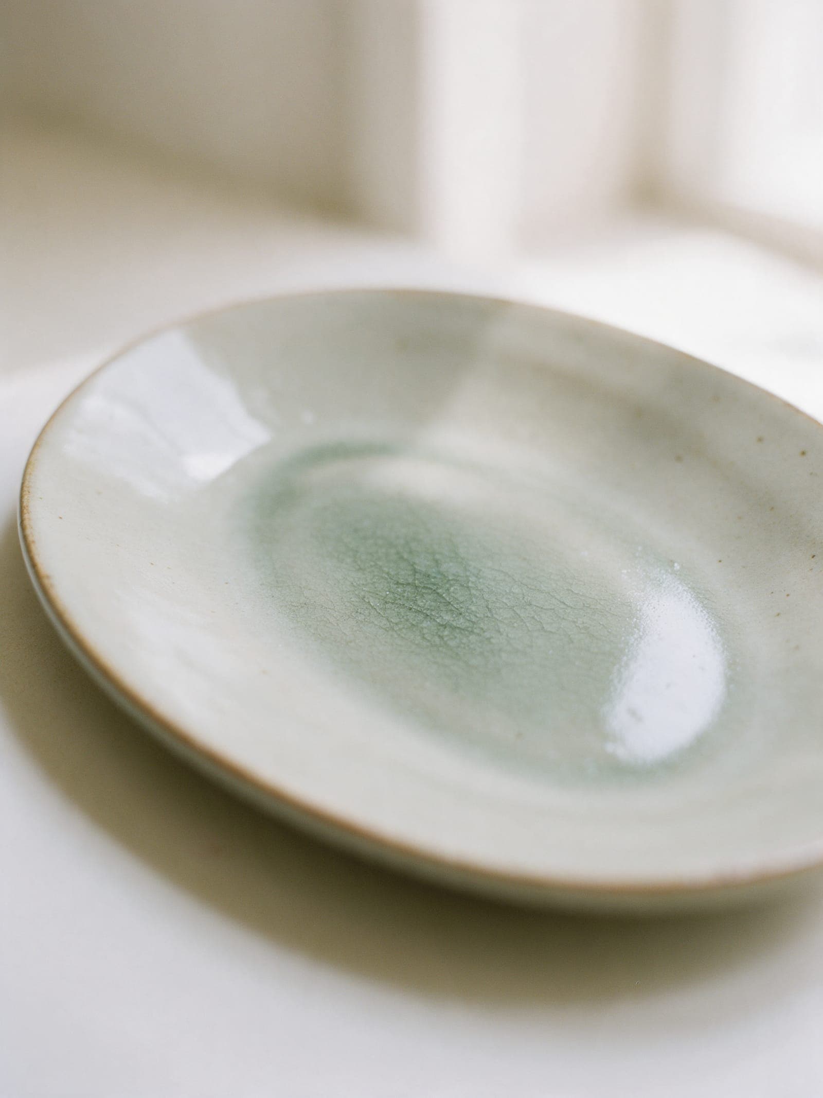Ash glaze pooled glassy green in the middle of the platter, with fine crackle