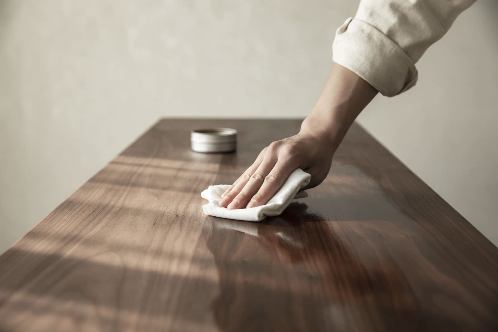 A hand rubbing hard oil into a walnut board with a cotton cloth