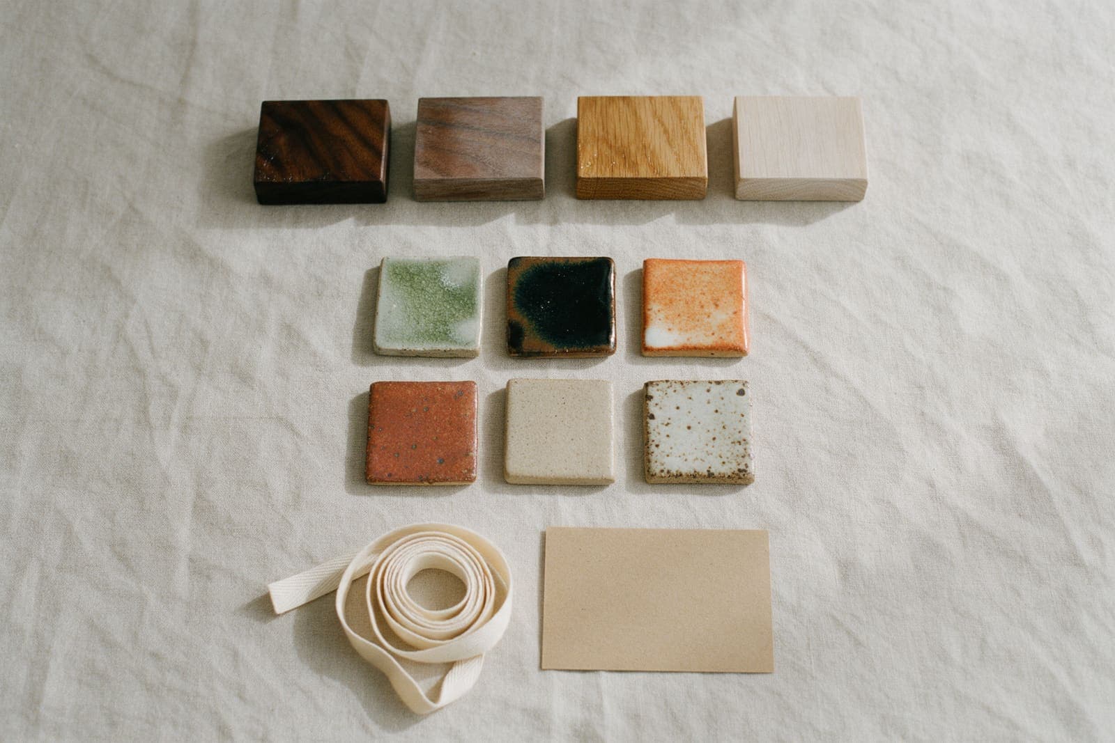 The trade sample set: walnut and white oak blocks, oiled and soaped, and six glaze tiles on linen