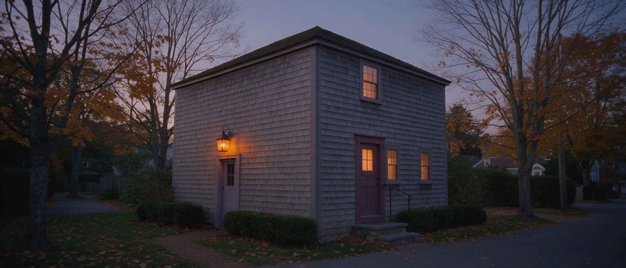 The clinic at dusk from Quillmere Lane: the plum front door on the right, and the side door under the lit lantern on the left.