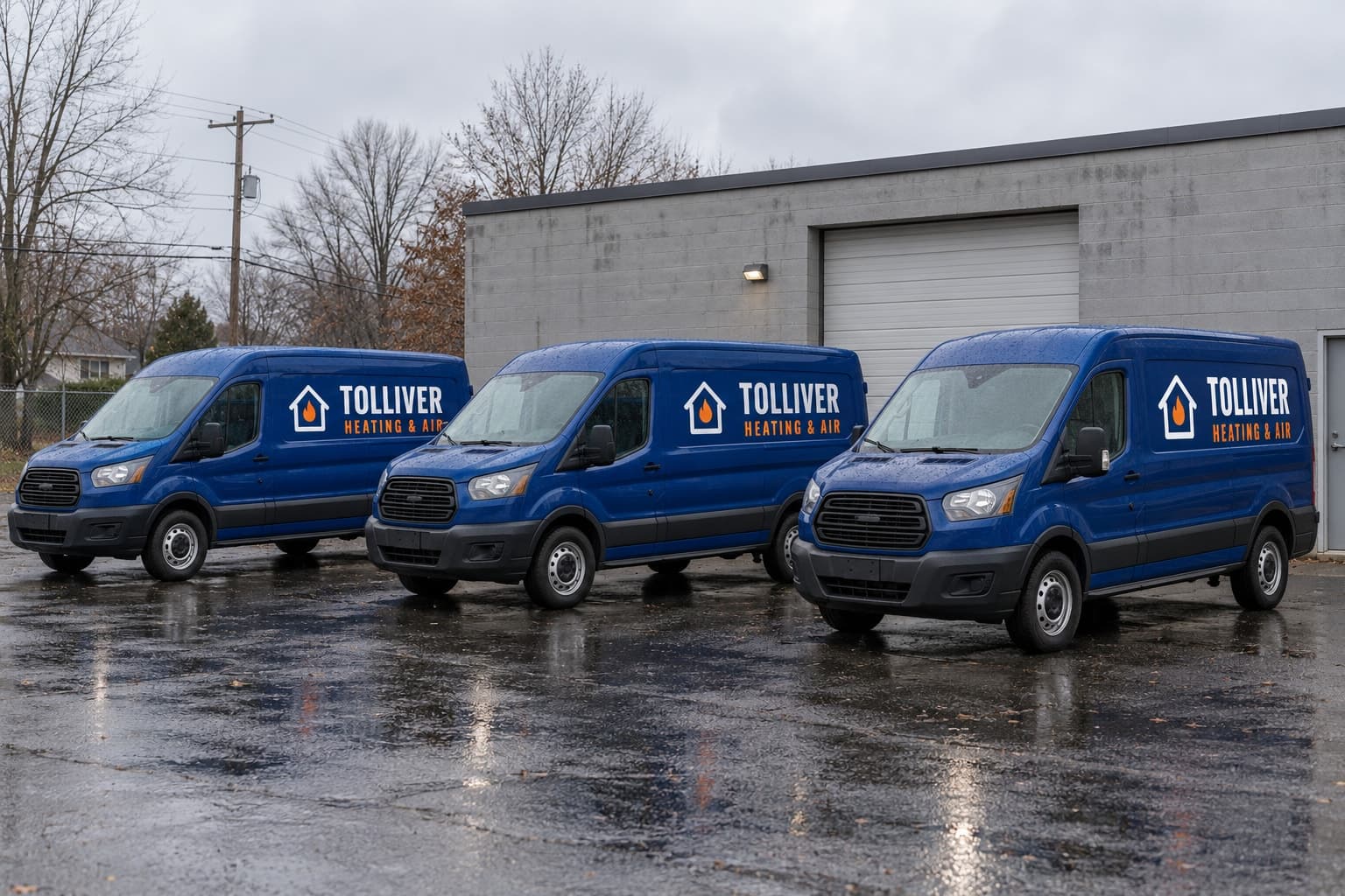 Three blue Tolliver Heating & Air service vans parked in front of the shop on a wet morning
