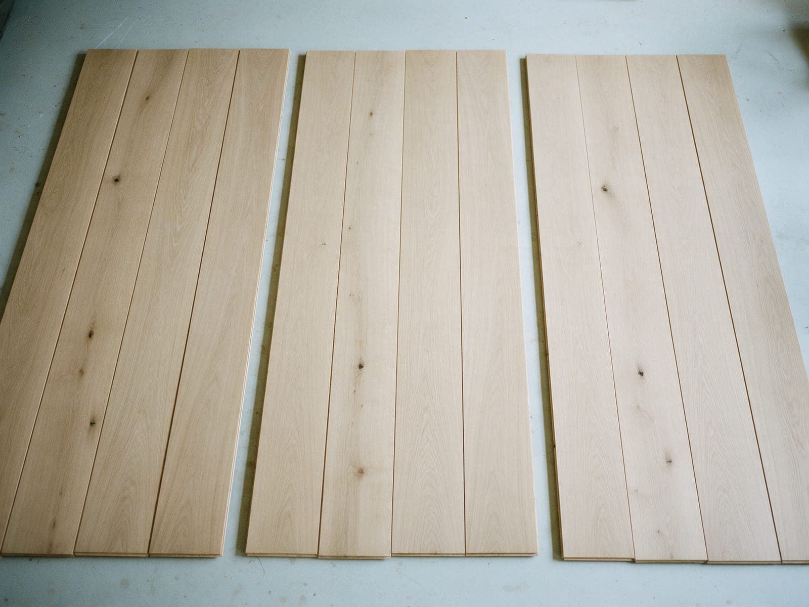 Three sets of four white oak boards laid out on the shop floor. Set 2 is chalked for the top, 183 cm.