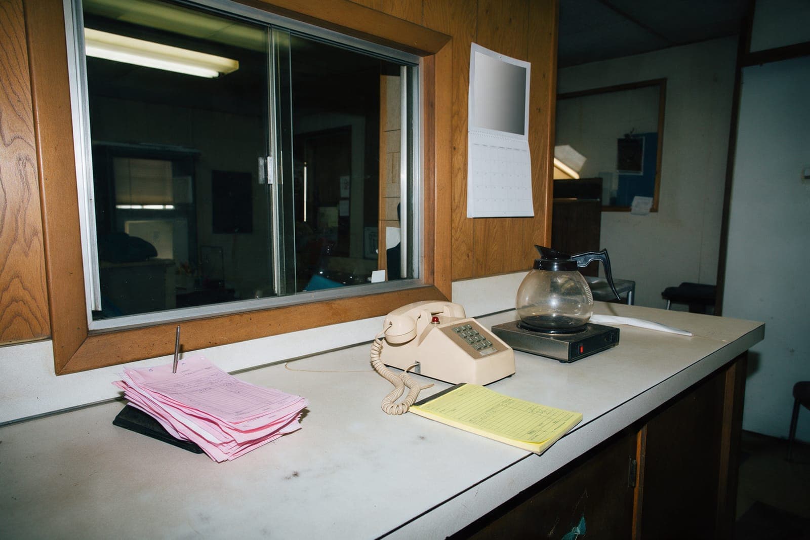 A contractor's office counter with a spike file of pink copies and a desk phone.