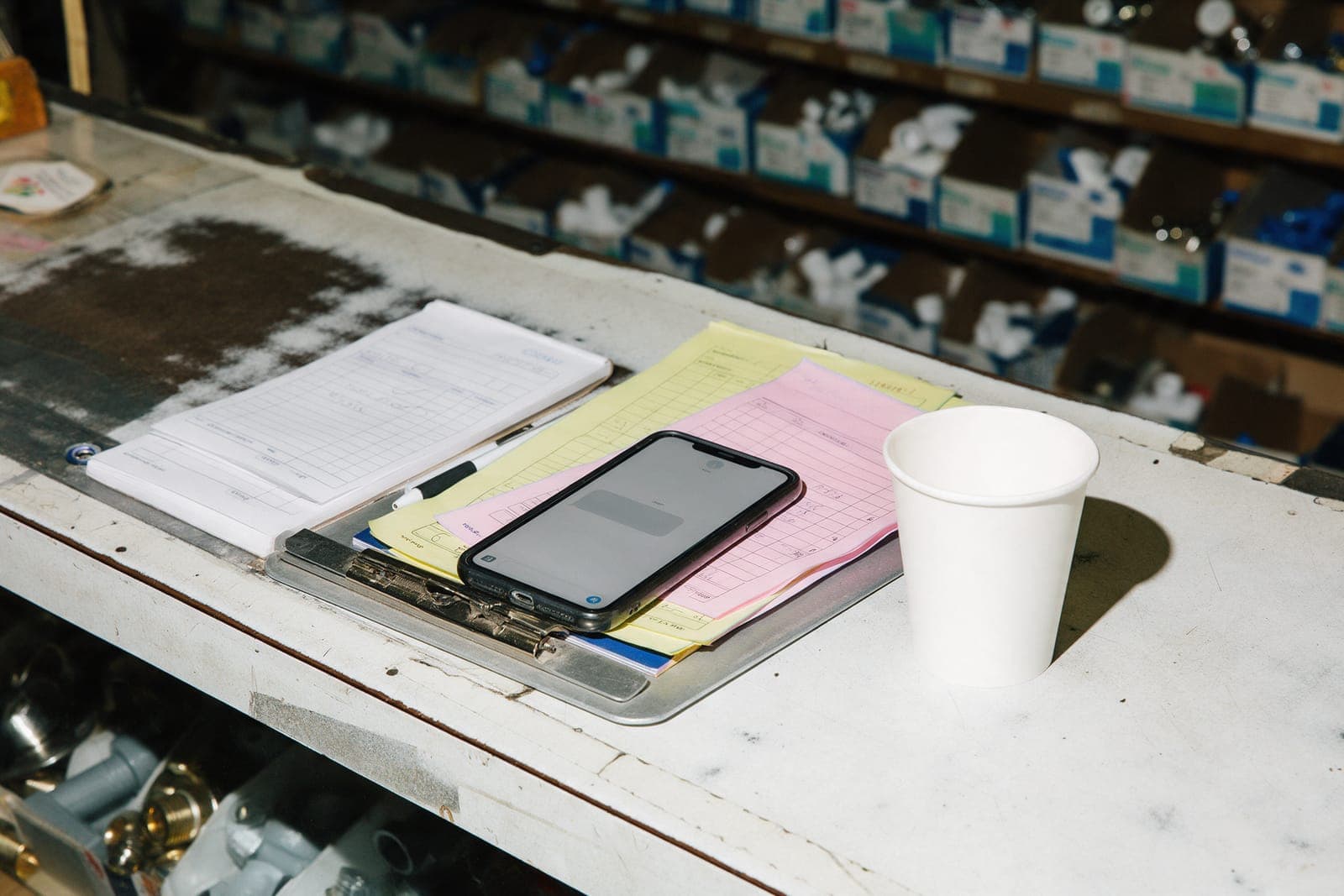 A phone on a clipboard next to a carbon estimate pad on a counter.