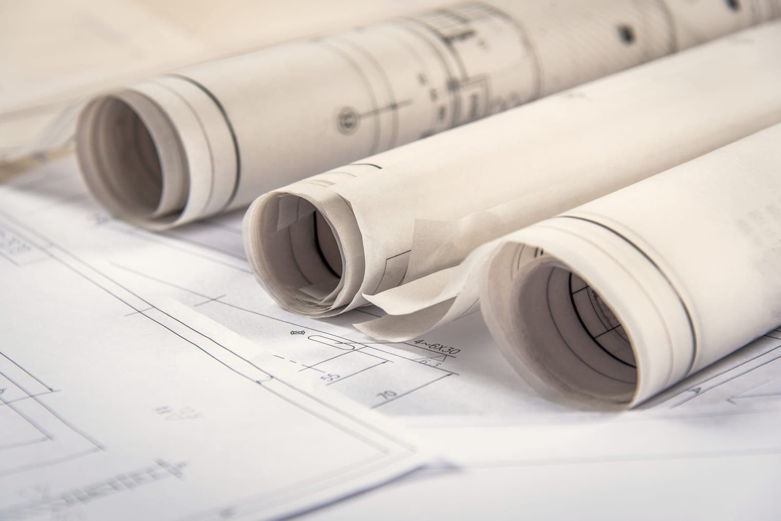 Rolled blueprints lying on an open set of floor plans.