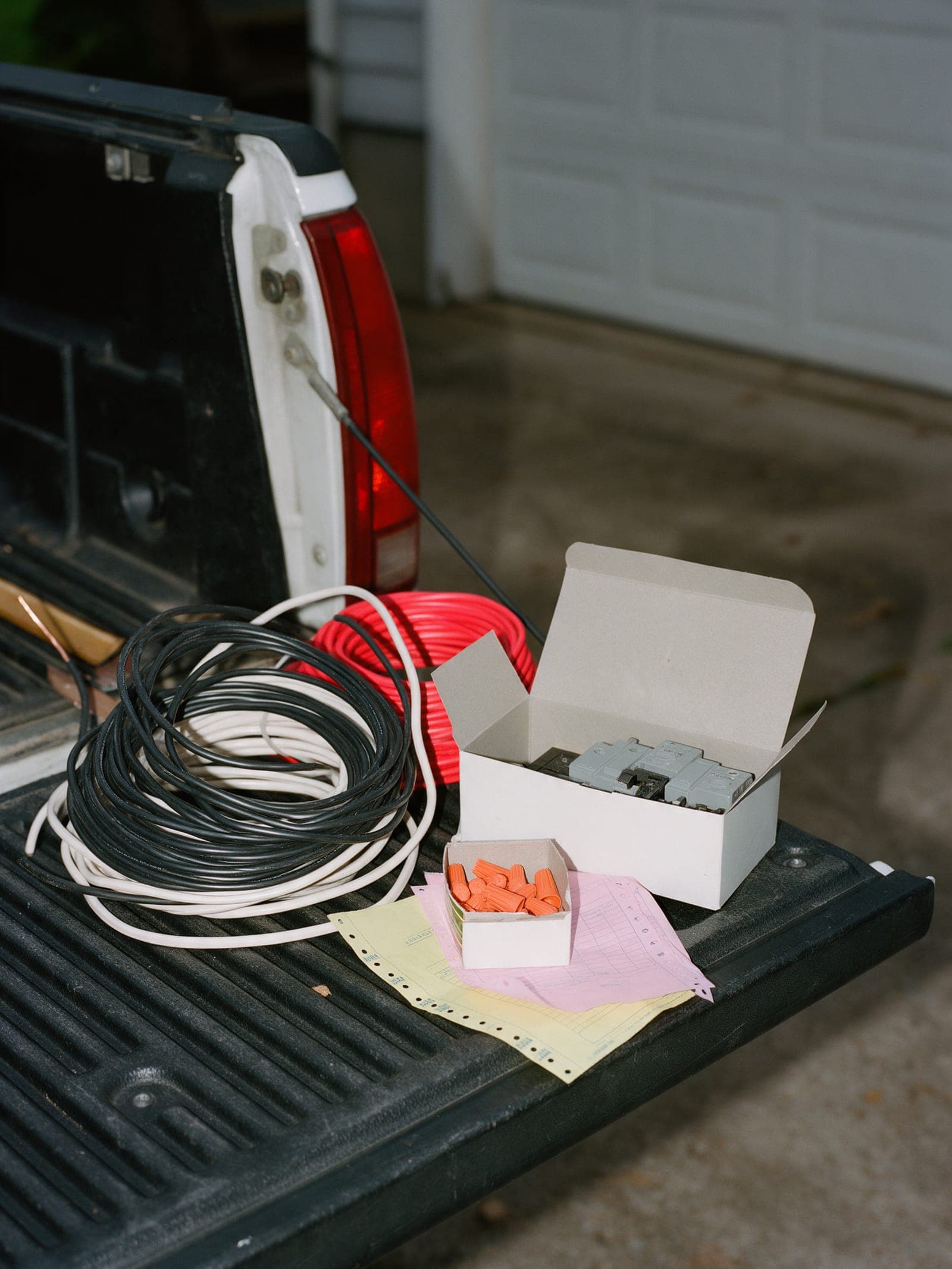 Wire coils and breakers on a truck tailgate with a yellow carbon copy.