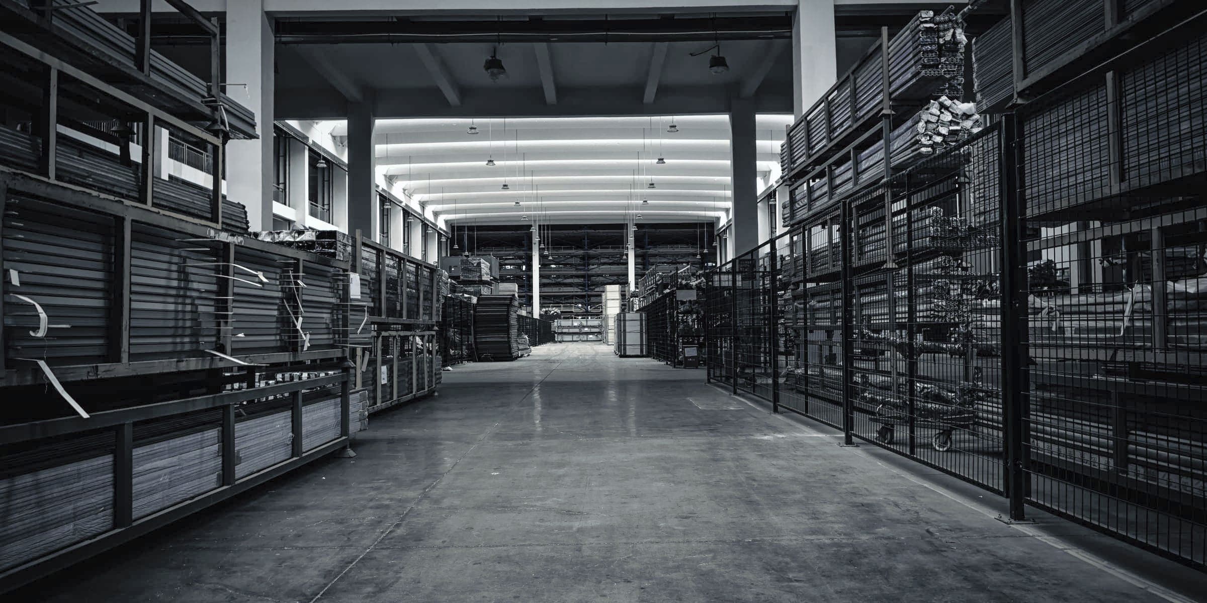 The stock aisle under the trusses: sheet and bar racked by grade and gauge on both sides