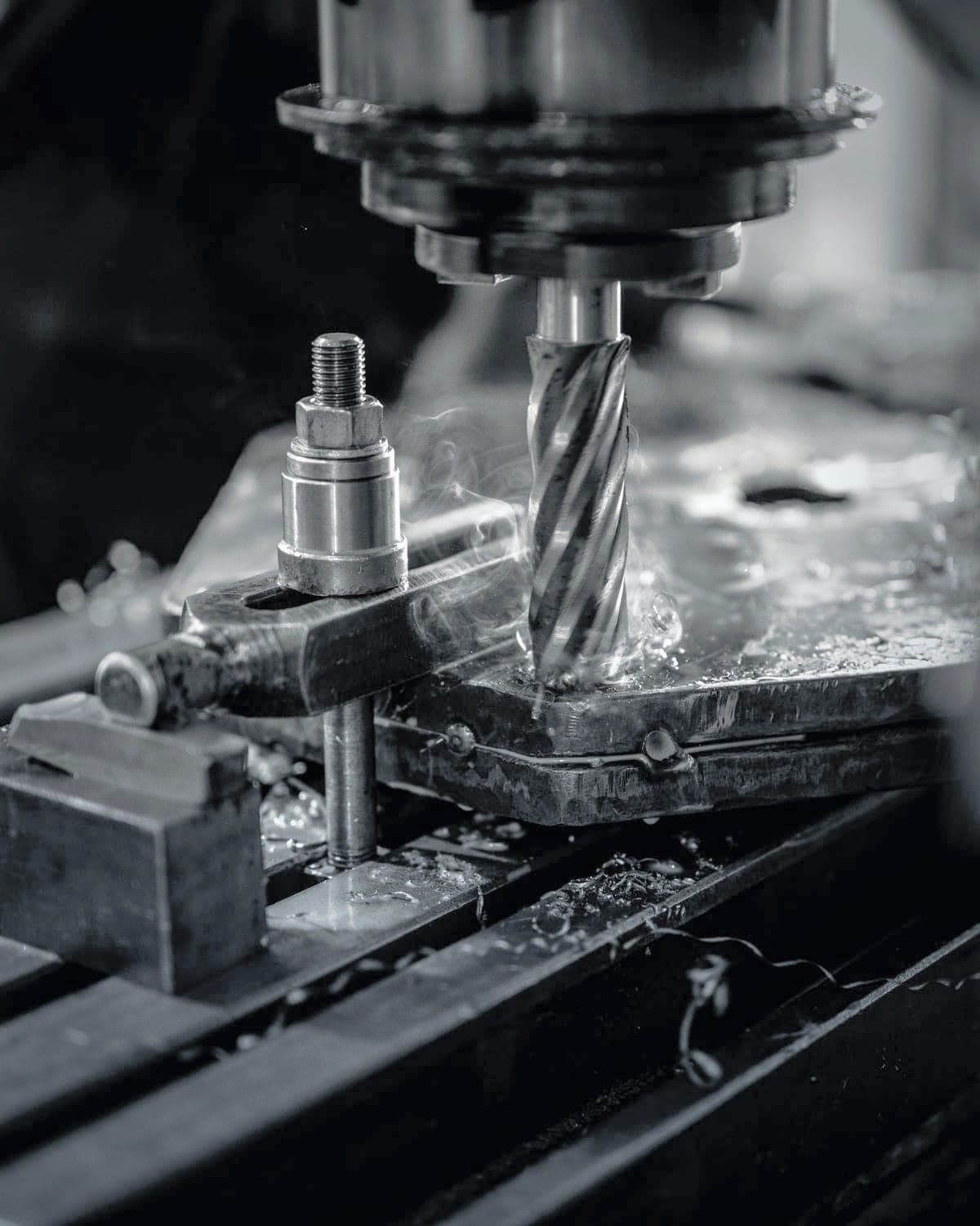 End mill cutting a plate clamped to the mill table, coolant smoking off the cut
